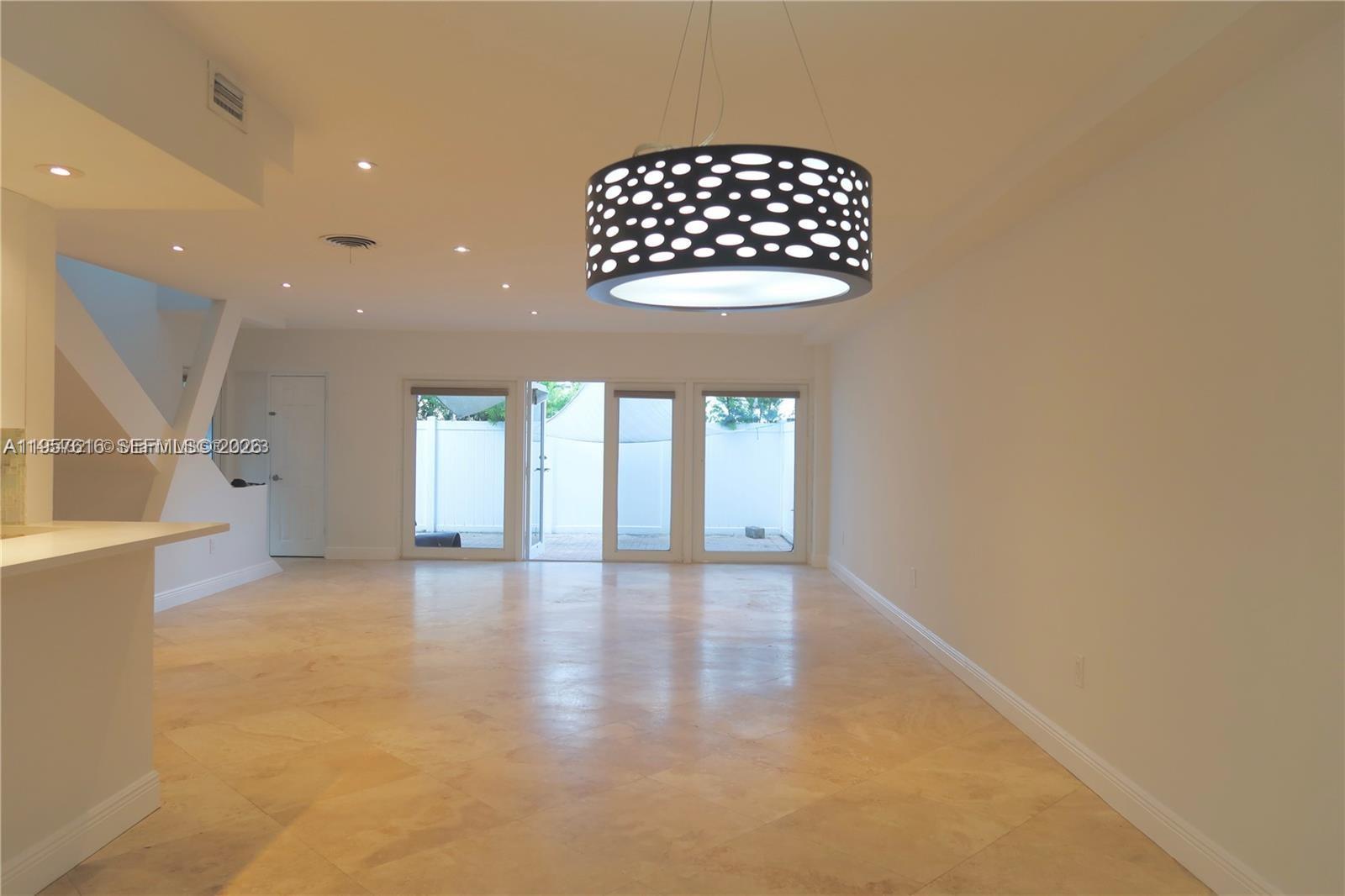 A bright, open-concept living area features light tile flooring and a modern patterned pendant light — 7312 Gary Ave # 7312, Miami Beach FL 33141, MIAMI BEACH, FL