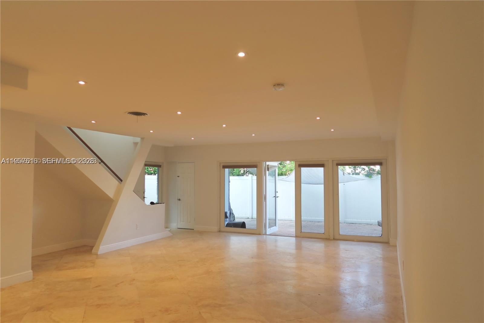 A spacious living area features tile flooring, recessed lighting, a staircase, and glass patio doors — 7312 Gary Ave # 7312, Miami Beach FL 33141, MIAMI BEACH, FL