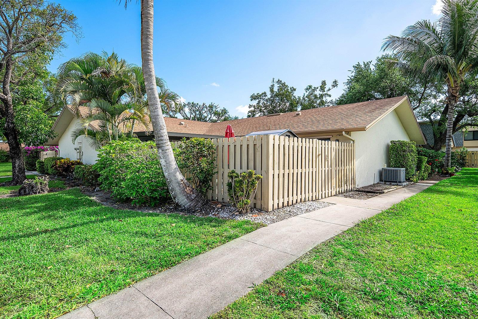 A tan house with a fenced patio area sits beside a concrete walkway and lawn — 777 NW 29th Avenue # A, Delray Beach FL 33445, DELRAY BEACH, FL