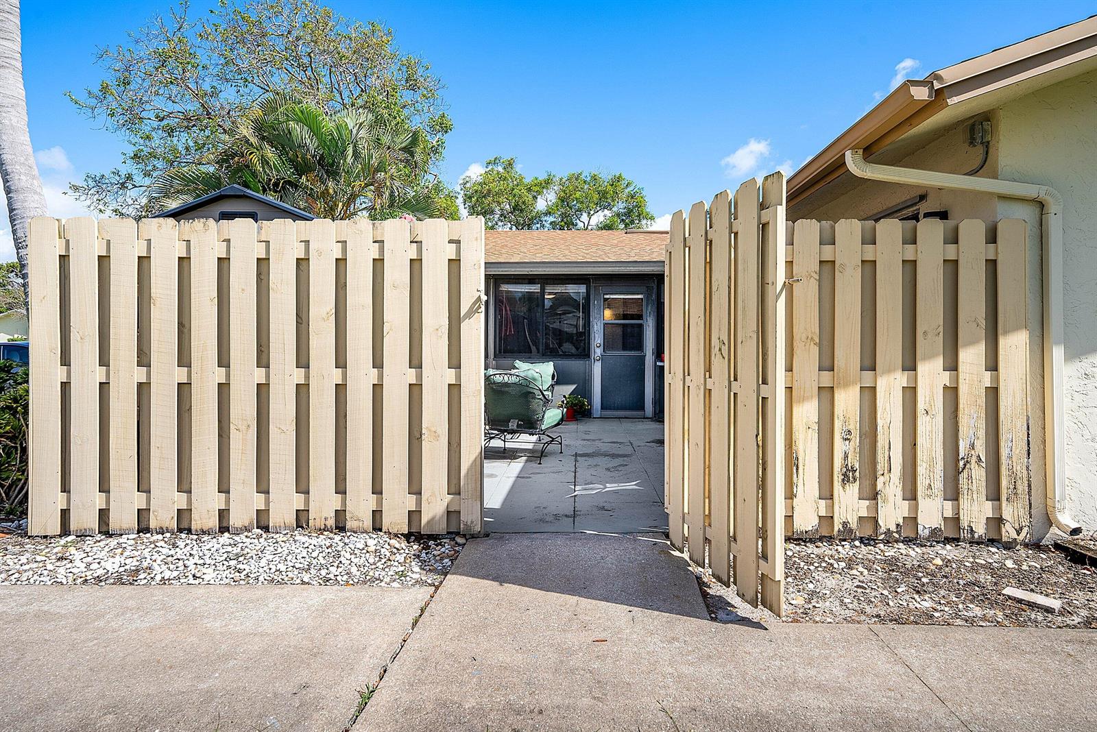 A concrete walkway leads through an open wooden gate to a small patio area — 777 NW 29th Avenue # A, Delray Beach FL 33445, DELRAY BEACH, FL