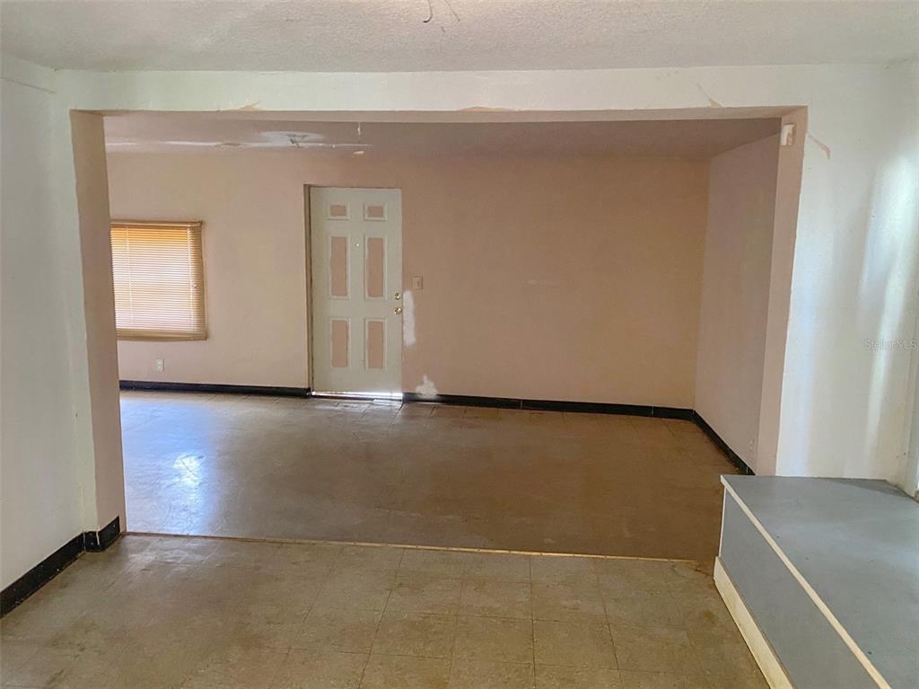 An interior view shows a room with beige walls, tile flooring, and a white door — 3716 E CLIFTON STREET, TAMPA, FL