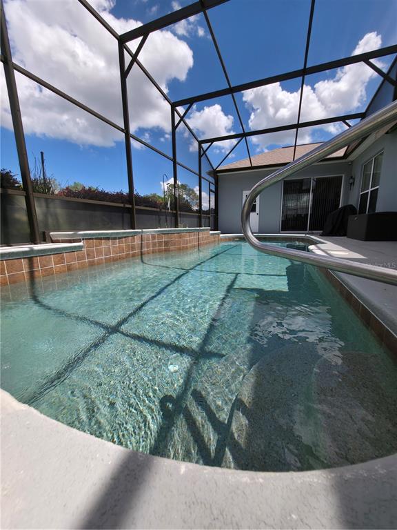 A rectangular swimming pool is enclosed by a screened lanai with a tiled wall feature — 4724 SABLE RIDGE COURT, LEESBURG, FL