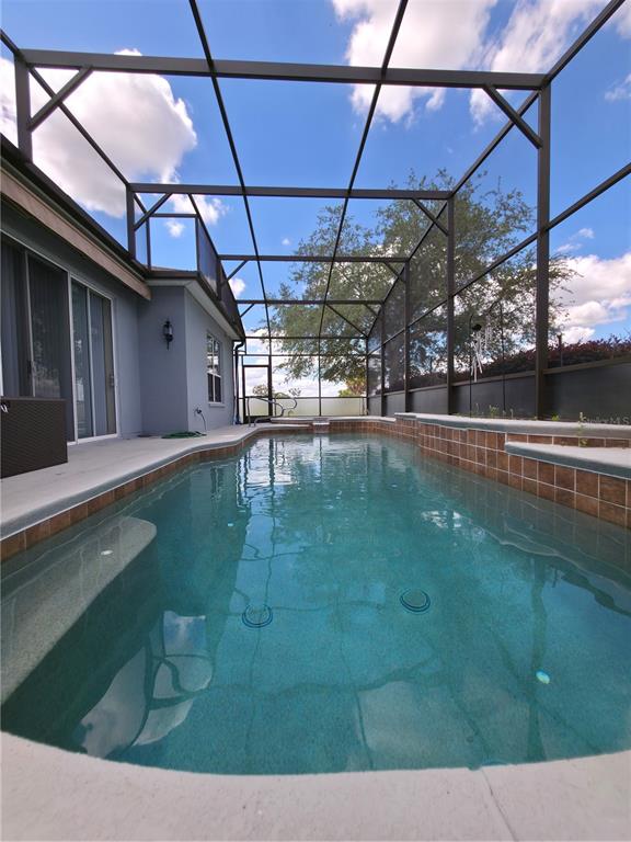 A rectangular swimming pool with a tiled border sits inside a screened-in lanai — 4724 SABLE RIDGE COURT, LEESBURG, FL