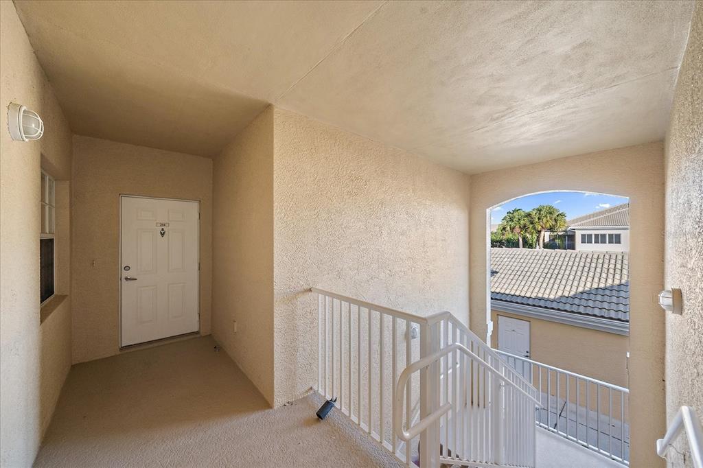 An exterior landing with a white door, a metal railing, and stairs leading downward — 6318 GRAND OAK CIRCLE UNIT 204, BRADENTON, FL
