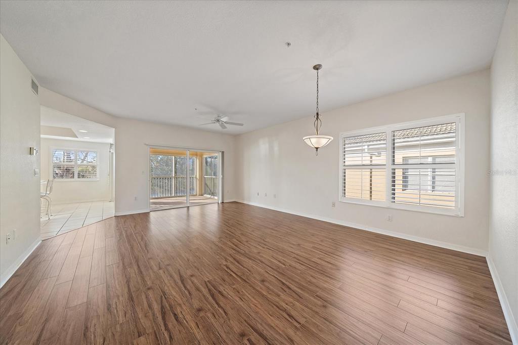 An empty living and dining area features wood-look flooring, a ceiling fan, and sliding doors — 6318 GRAND OAK CIRCLE UNIT 204, BRADENTON, FL