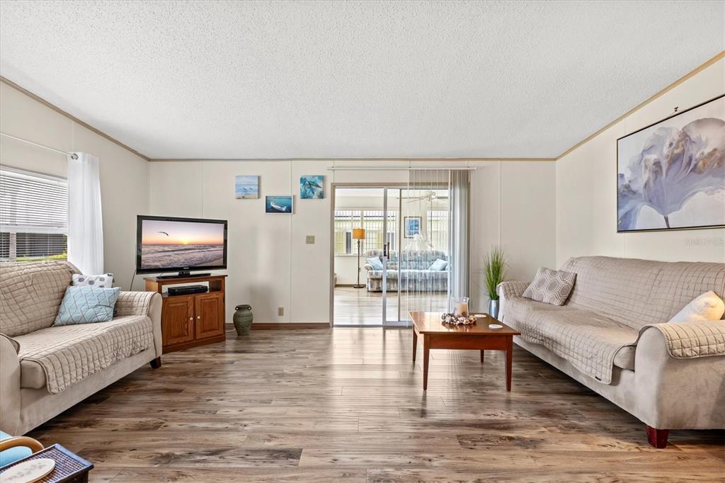 A living room features wood-look flooring, two beige sofas, a coffee table, and a television — 58 PARTRIDGE AVENUE, ELLENTON, FL