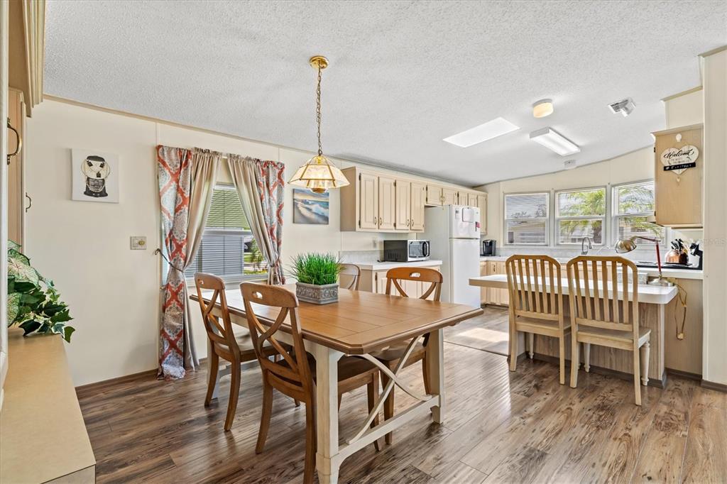 A dining area with a wooden table and chairs sits adjacent to a kitchen — 58 PARTRIDGE AVENUE, ELLENTON, FL