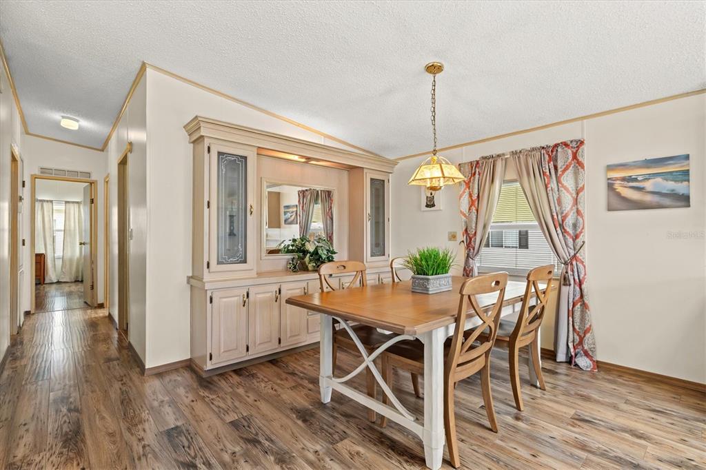 A dining room features a wooden table, chairs, a built-in hutch, and wood-look flooring — 58 PARTRIDGE AVENUE, ELLENTON, FL