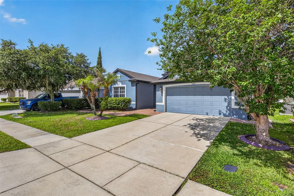 A blue single-story house features a two-car garage, a concrete driveway, and mature landscaping — 2922 WILLOW CREEK LANE, KISSIMMEE, FL