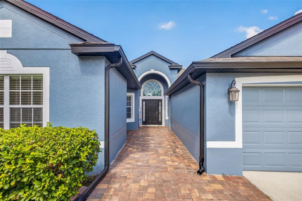 A blue house exterior features a stone-paved walkway leading to a dark front door — 2922 WILLOW CREEK LANE, KISSIMMEE, FL