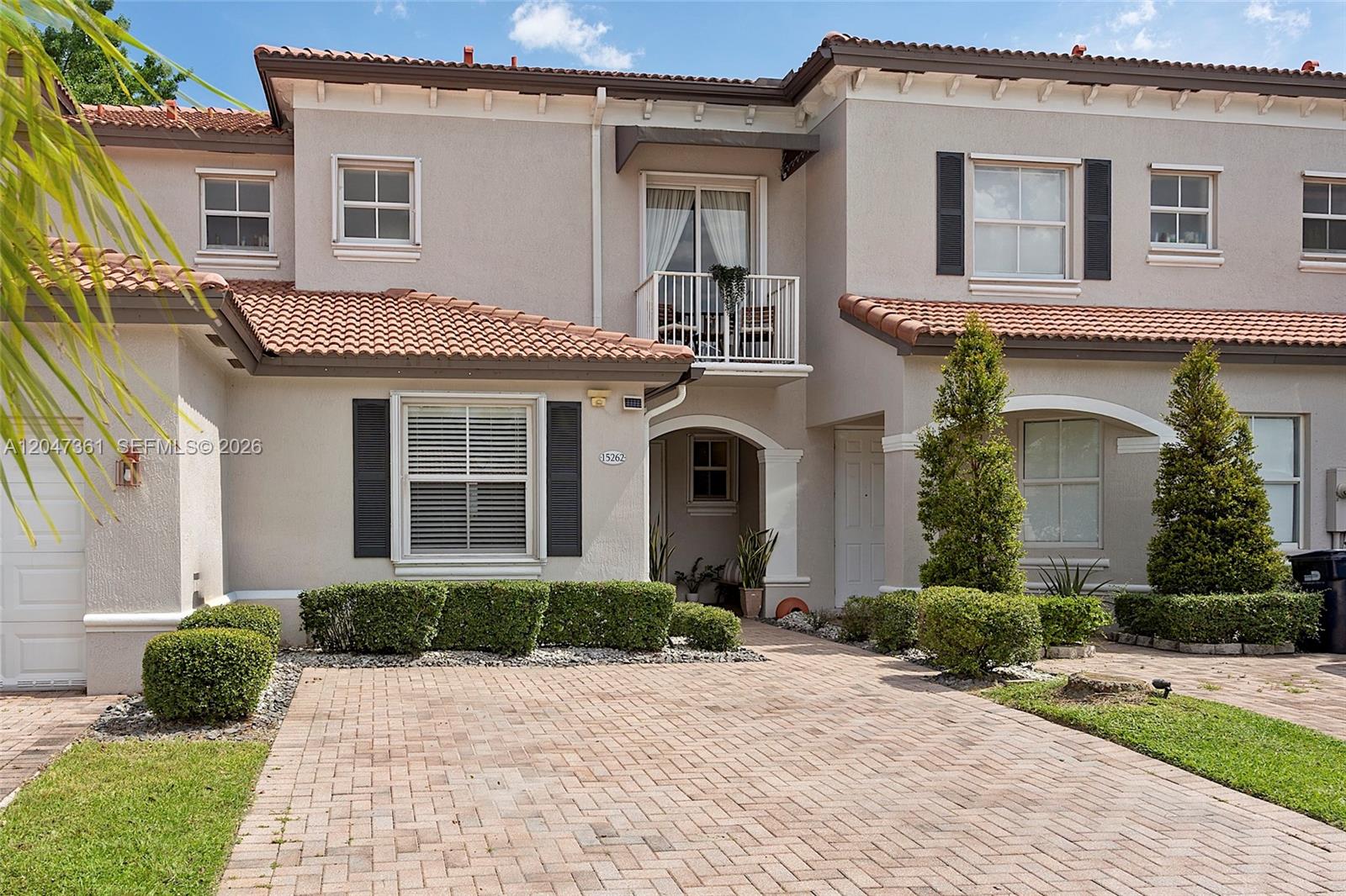 A two-story townhouse features a tiled roof, a brick paver driveway, and a small balcony — 15262 SW 91st Ln, Miami FL 33196, MIAMI, FL