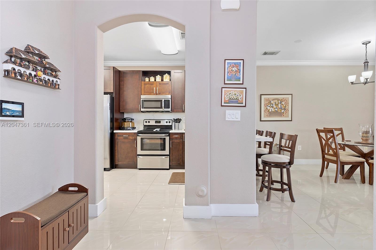 A view through an arched doorway shows a kitchen with dark cabinets and tile floors — 15262 SW 91st Ln, Miami FL 33196, MIAMI, FL