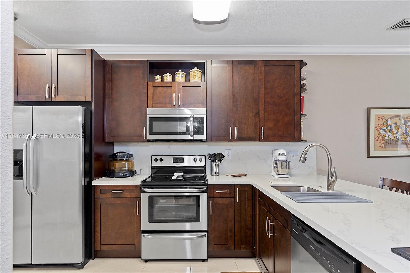 A kitchen features dark wood cabinets, stainless steel appliances, and white quartz countertops — 15262 SW 91st Ln, Miami FL 33196, MIAMI, FL