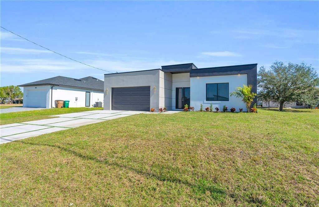 A modern, single-story house with a flat roof, gray garage, and white stucco exterior — 3924 NW 38TH STREET, CAPE CORAL, FL