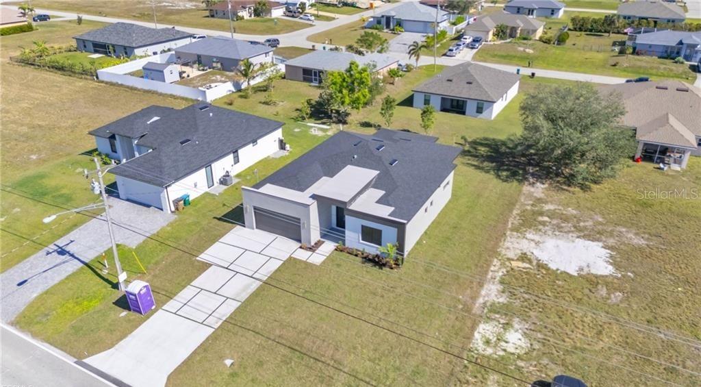 An aerial view shows a modern single-story house with a dark roof and concrete driveway — 3924 NW 38TH STREET, CAPE CORAL, FL