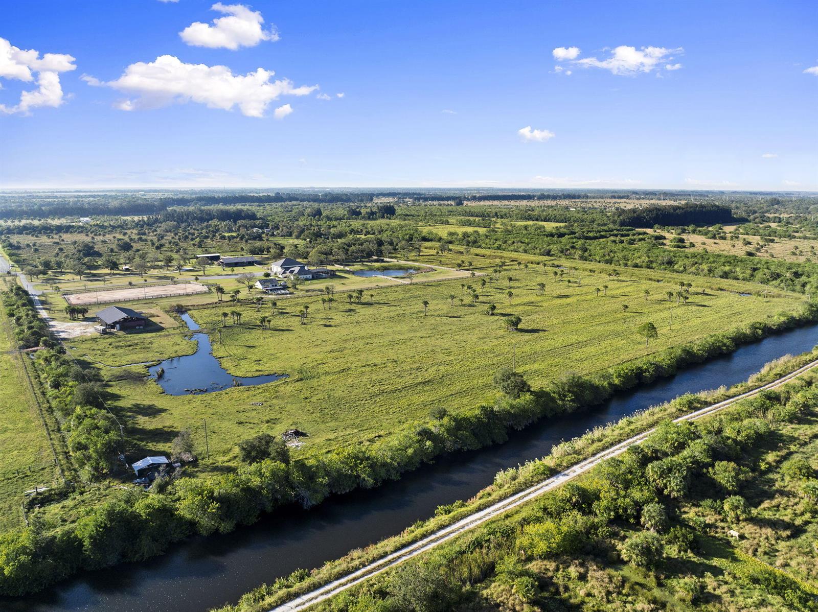 An aerial view shows a large rural property with a canal, pastures, and several buildings — 4044 Johnston Road, Fort Pierce FL 34951, FORT PIERCE, FL