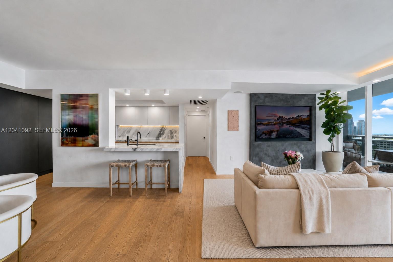 A modern living room features a kitchen island, hardwood floors, and a wall-mounted television — 400 Alton Rd # 1206, Miami Beach FL 33139, MIAMI BEACH, FL