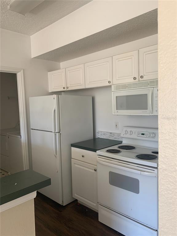 A kitchen features white cabinets, white appliances, and a dark countertop — 5578 METROWEST UNIT 206, ORLANDO, FL