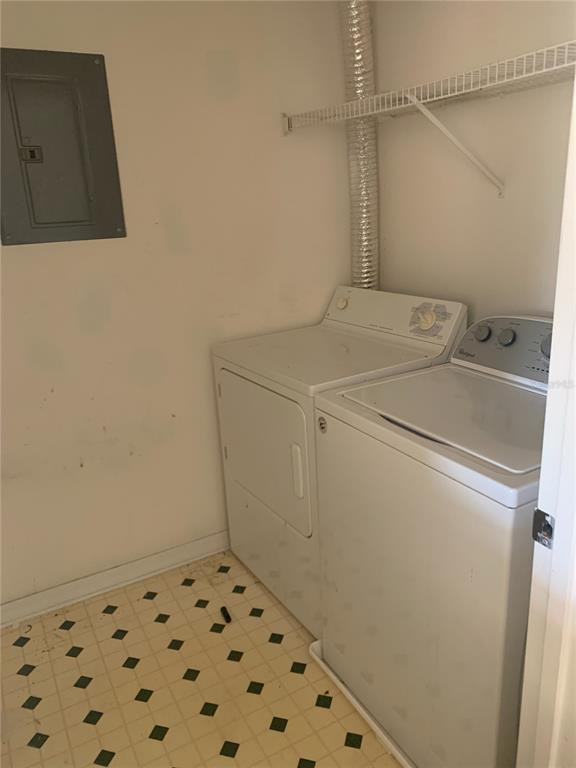 A laundry closet contains a white washer and dryer, a wire shelf, and a breaker panel — 5578 METROWEST UNIT 206, ORLANDO, FL