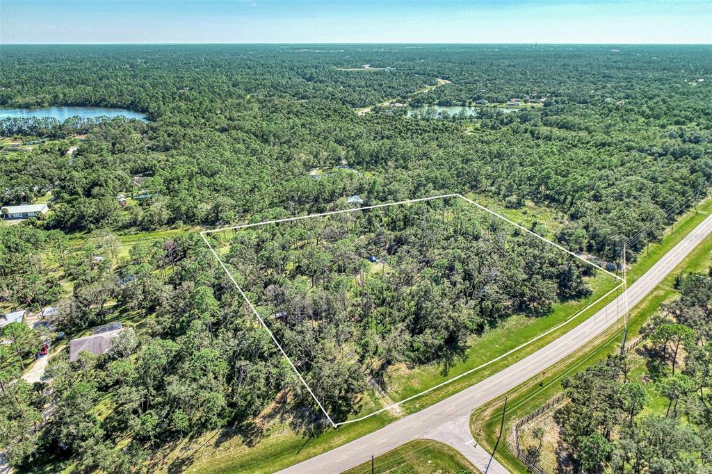 An aerial view shows a rectangular plot of wooded land bordered by a paved road — Lot 2 TROPICAIRE BOULEVARD, NORTH PORT, FL