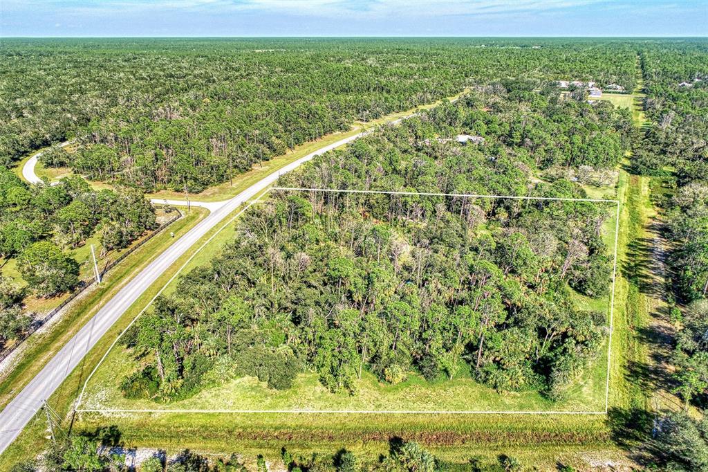 An aerial view shows a rectangular, wooded plot of land bordered by a paved road — Lot 2 TROPICAIRE BOULEVARD, NORTH PORT, FL