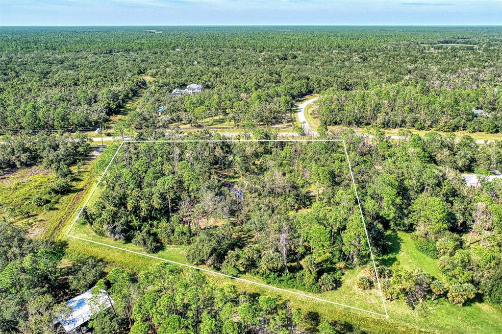 An aerial view shows a rectangular plot of land outlined in white amidst dense forest — Lot 2 TROPICAIRE BOULEVARD, NORTH PORT, FL