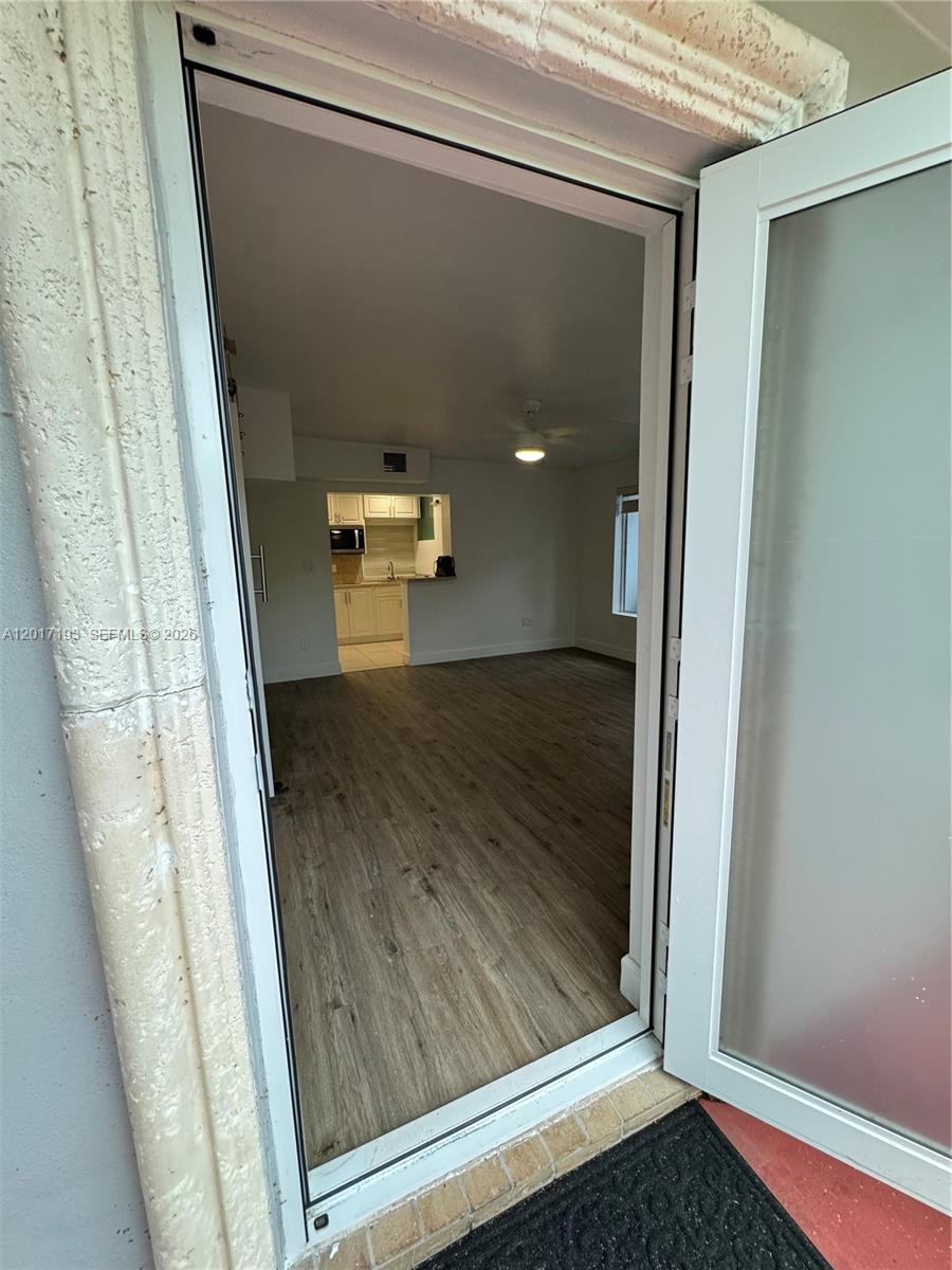 A bright, empty living room features light wood-look flooring, white walls, and a ceiling fan — 235 SW 64th Ave # 2B, Miami FL 33144, MIAMI, FL