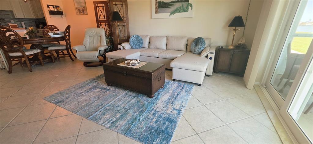 A living room features a beige sectional sofa, a blue area rug, and a wooden chest — 400 64TH AVENUE UNIT 103w, ST PETE BEACH, FL