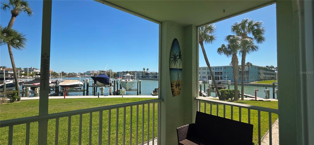 A screened-in patio overlooks a marina with several boats docked along the water — 400 64TH AVENUE UNIT 103w, ST PETE BEACH, FL