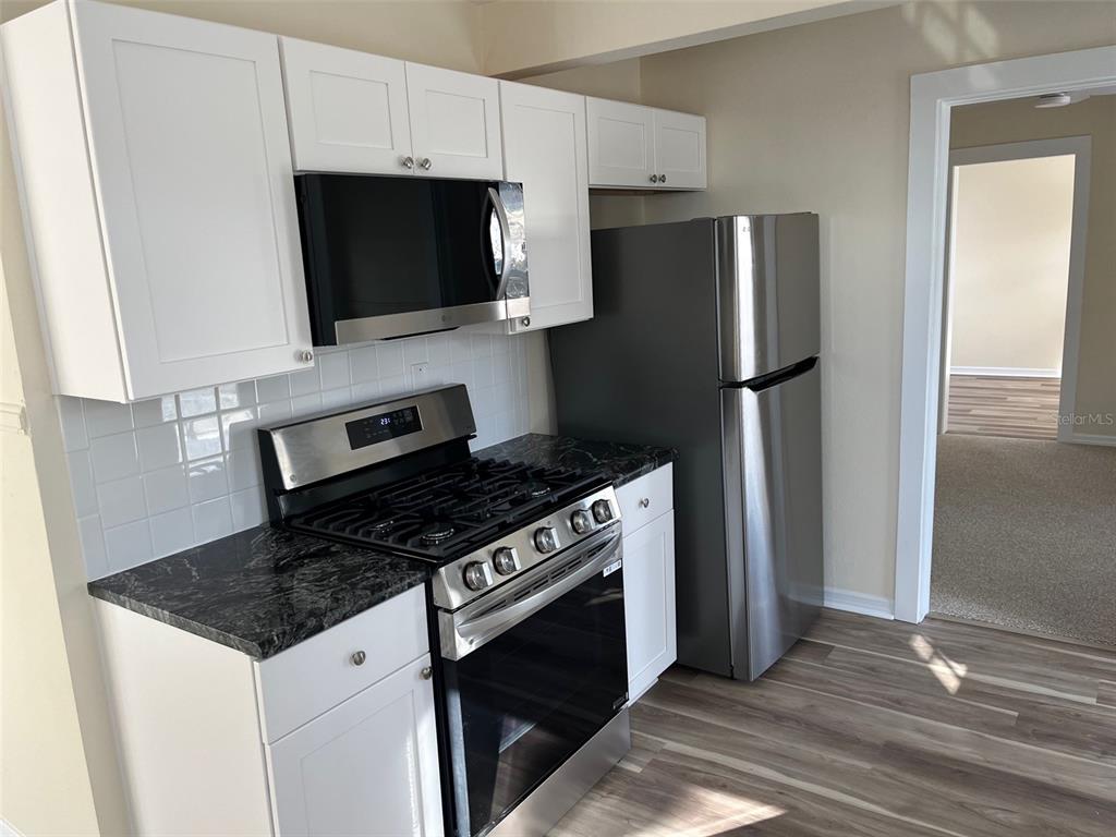 A kitchen features white cabinets, stainless steel appliances, and dark granite countertops — 8401 W GULF BOULEVARD, TREASURE ISLAND, FL