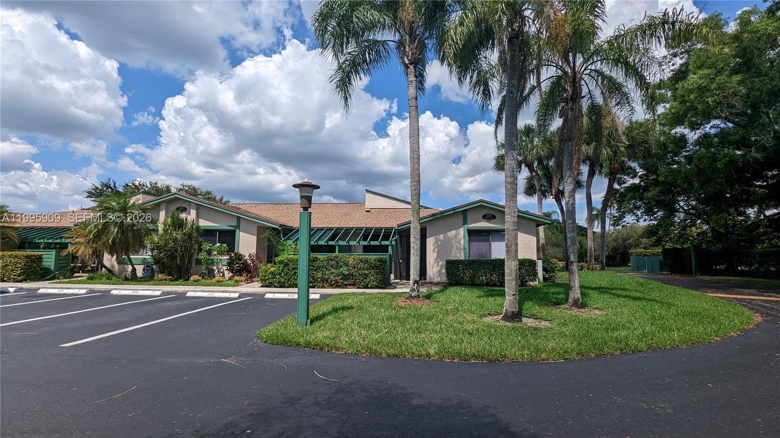 A single-story building with a tan exterior, green trim, and palm trees in the front — 460 Lakeview Dr # 4, Weston FL 33326, WESTON, FL