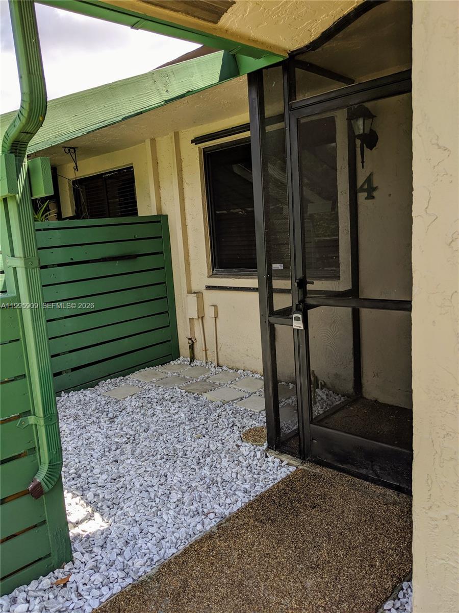 The exterior entrance features a screen door, a gravel patio, and a green privacy fence — 460 Lakeview Dr # 4, Weston FL 33326, WESTON, FL