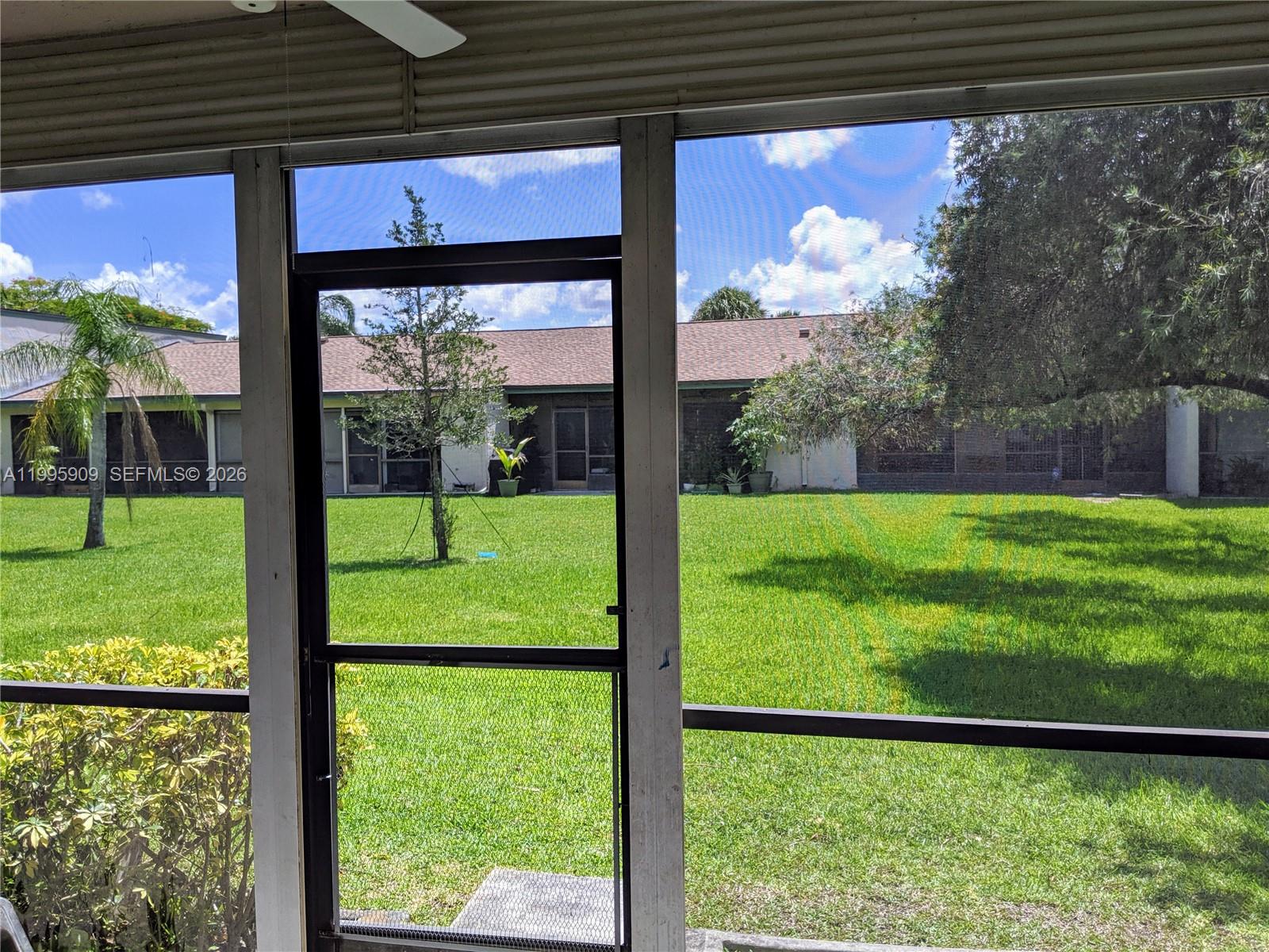 A view of a grassy backyard and neighboring houses seen through a screened-in porch — 460 Lakeview Dr # 4, Weston FL 33326, WESTON, FL