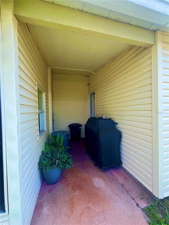 A covered outdoor patio with light yellow siding, a potted plant, and a covered grill — 5716 PAWNEE STREET, ZEPHYRHILLS, FL