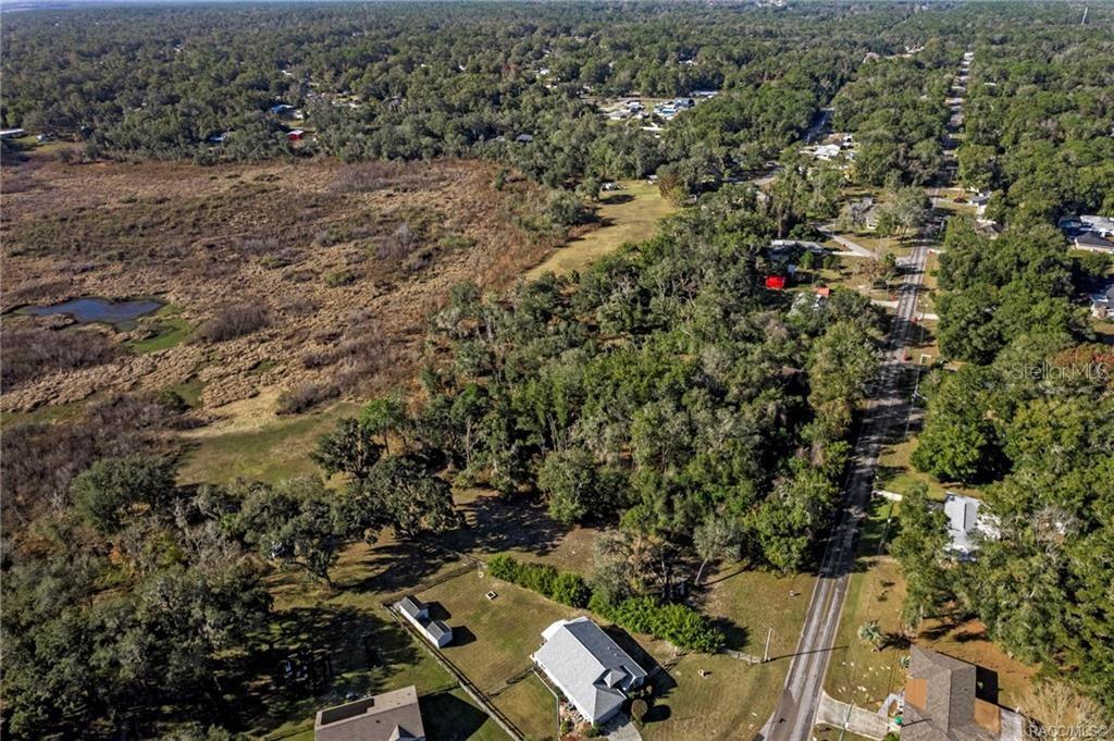 An aerial view shows a residential property with a house, surrounding trees, and nearby wetlands — 6616 E MALVERNE STREET, INVERNESS, FL