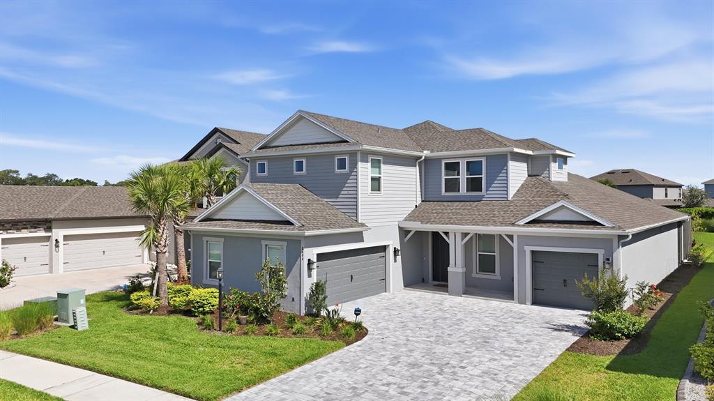 A two-story gray house with a paved driveway, two garages, and a manicured front lawn — 8494 SNOWFALL STREET, SARASOTA, FL
