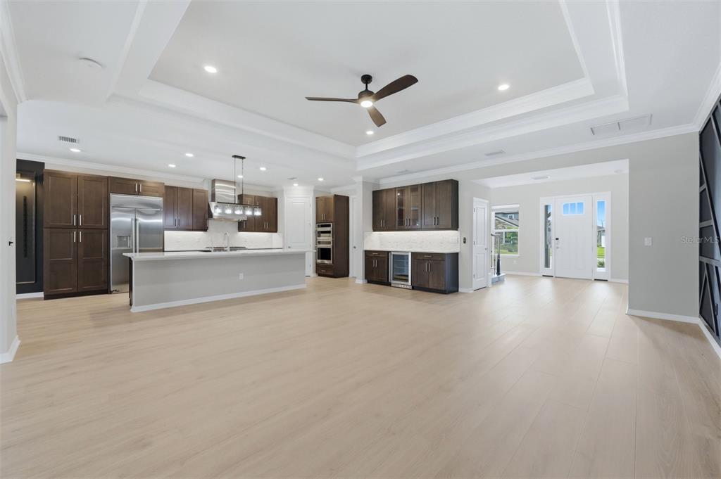 A spacious open-concept kitchen and living area with dark wood cabinets and light flooring — 8494 SNOWFALL STREET, SARASOTA, FL