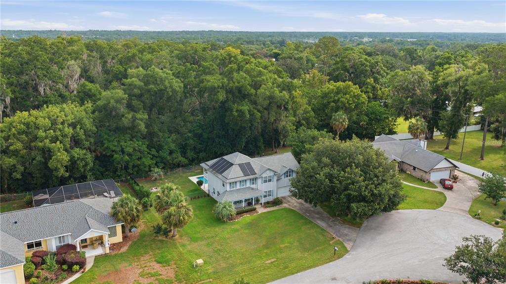 An aerial view shows a two-story house with solar panels and a pool in a neighborhood — 3015 SE 40TH STREET, OCALA, FL