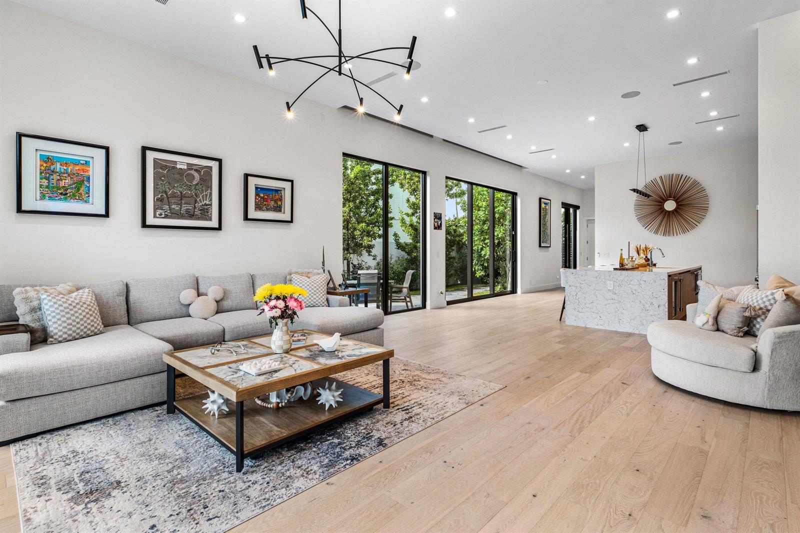 A modern open-concept living room features a gray sectional, marble coffee table, and kitchen island — 917 NE 8th Avenue, Delray Beach FL 33483, DELRAY BEACH, FL