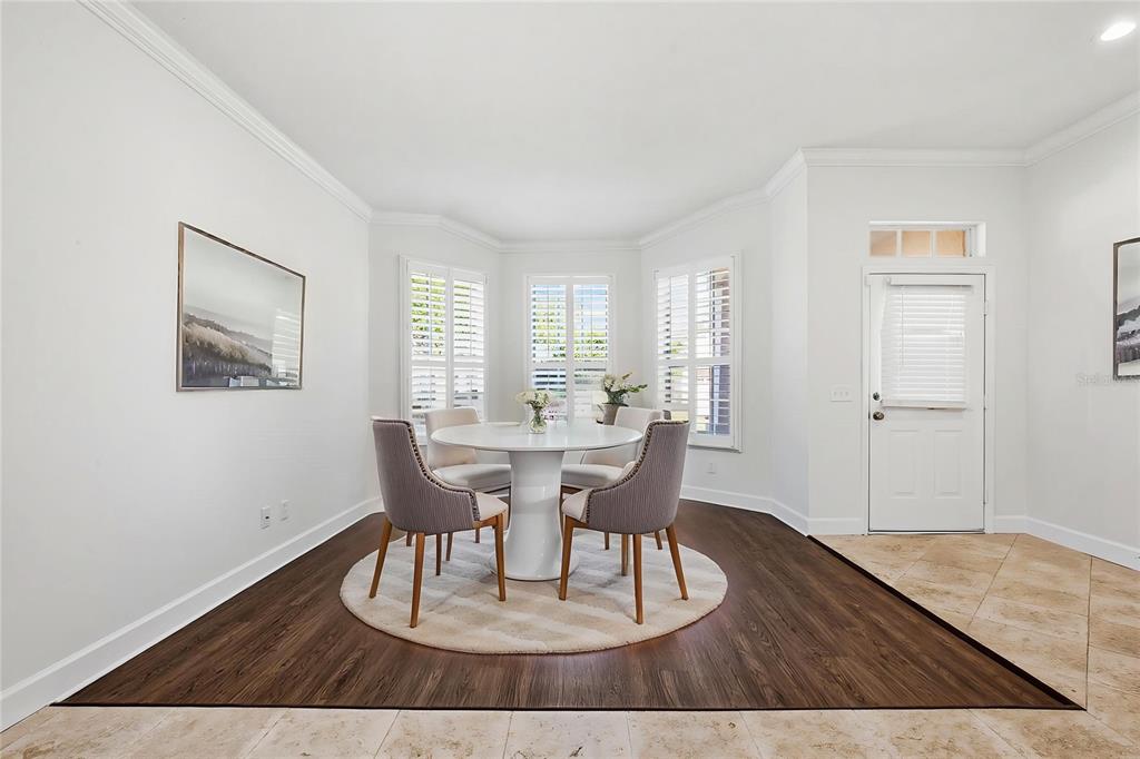 A dining area features a round table, four chairs, dark wood flooring, and white walls — 19409 MELODY FAIR PLACE, LUTZ, FL