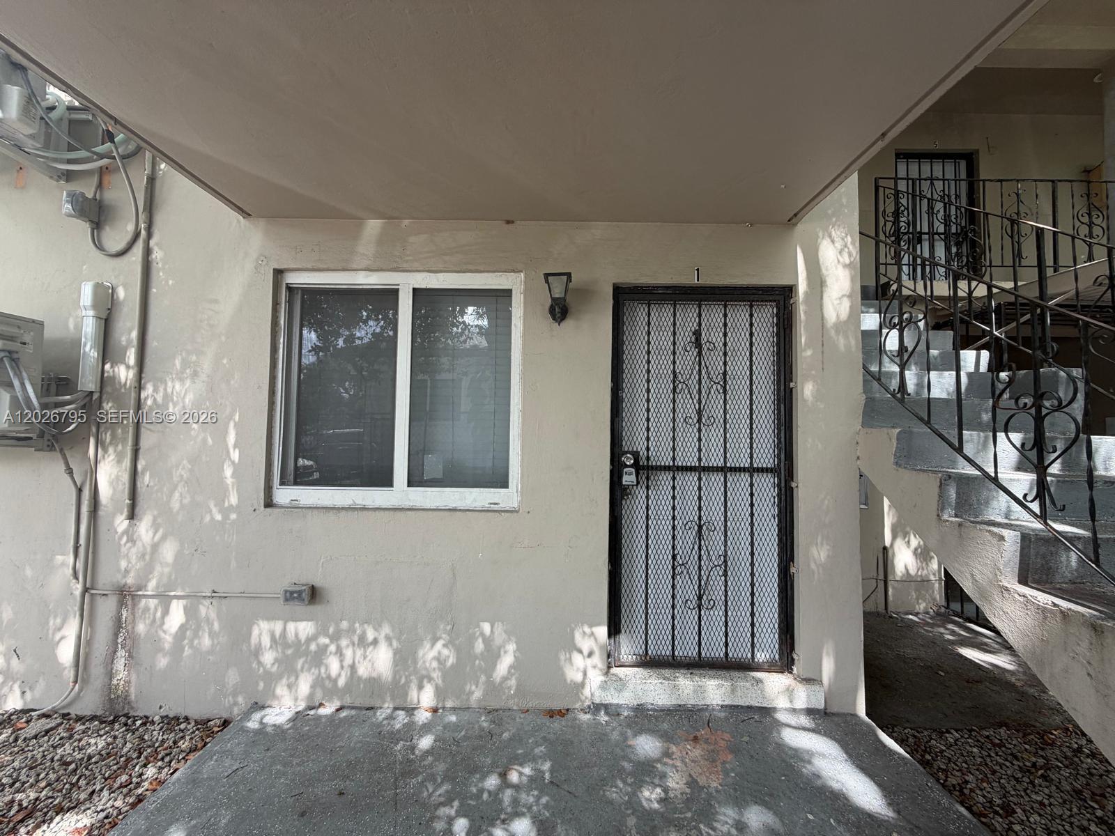 The exterior view shows a ground-level apartment entrance with a security door and window — 1844 NW 19th St # 1, Miami FL 33125, MIAMI, FL