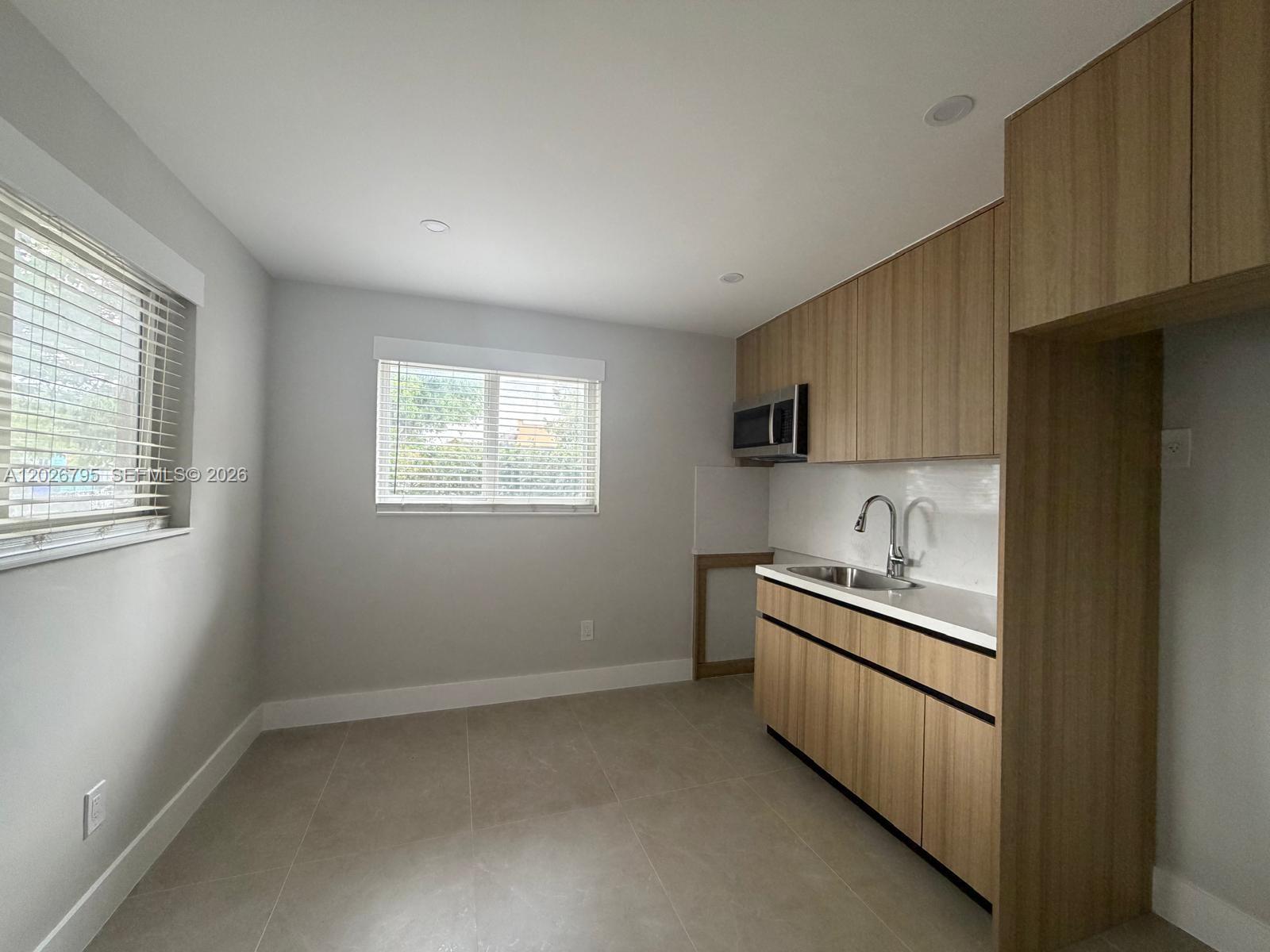 A kitchen features light wood cabinets, a stainless steel sink, and large floor tiles — 1844 NW 19th St # 1, Miami FL 33125, MIAMI, FL