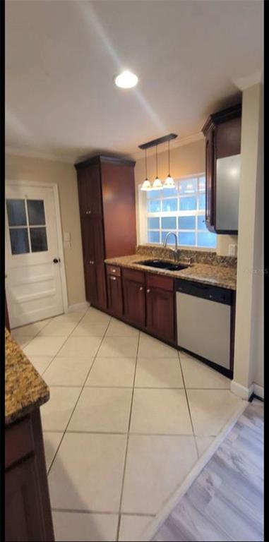 A kitchen features dark wood cabinets, granite countertops, a stainless steel dishwasher, and tile flooring — 3805 NW 50TH STREET, GAINESVILLE, FL