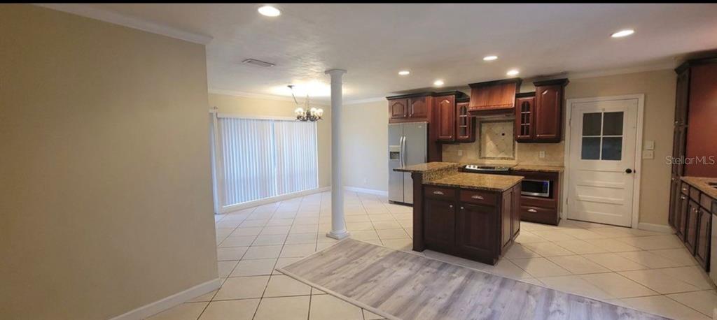 A kitchen with dark wood cabinets, granite countertops, and a central island with tile flooring — 3805 NW 50TH STREET, GAINESVILLE, FL