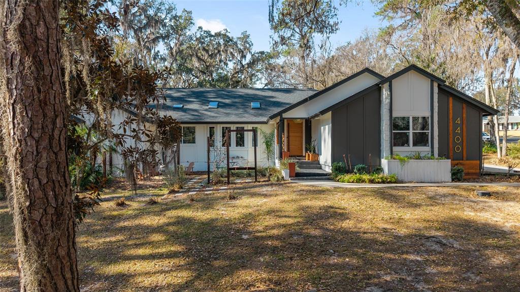 A single-story house with a dark gray exterior, white trim, and a wood-paneled front entrance — 4400 SW 20TH AVENUE, OCALA, FL