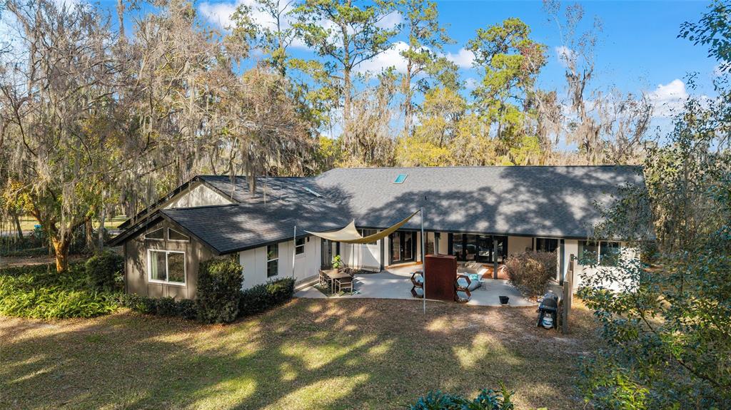 A single-story house with a gray roof, white siding, and a concrete patio with shade — 4400 SW 20TH AVENUE, OCALA, FL