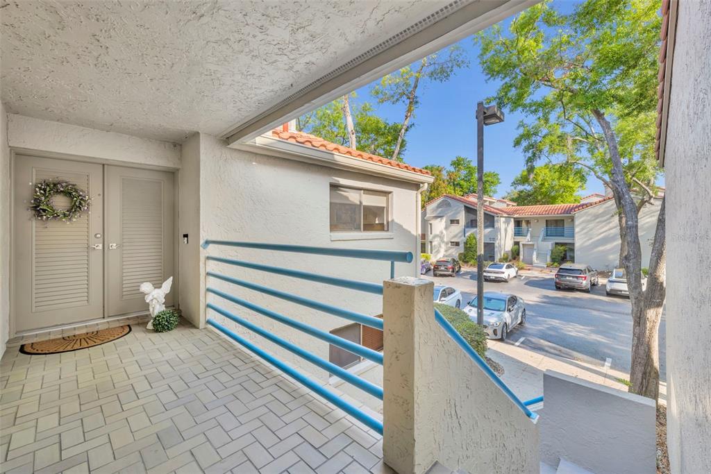 An elevated outdoor walkway with blue railings overlooks a parking lot and apartment buildings — 1000 WINDERLEY PLACE UNIT 239, MAITLAND, FL