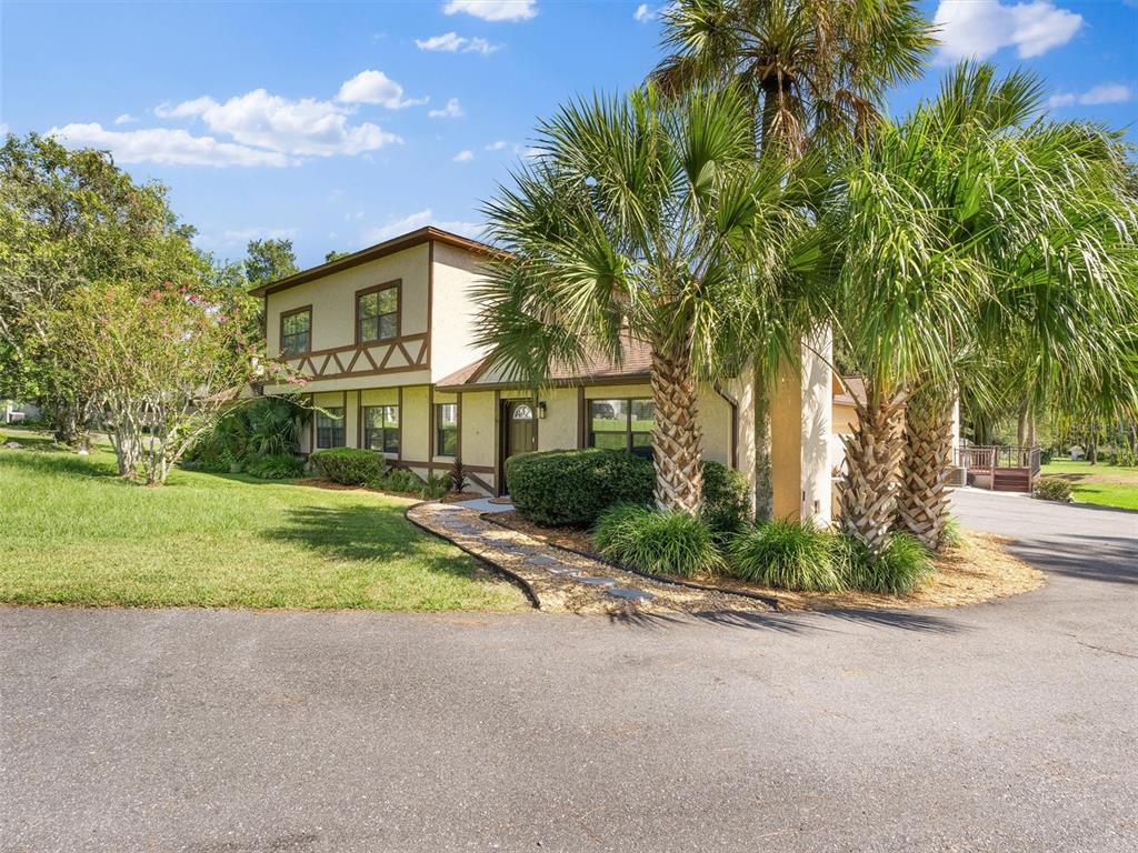 A two-story house with stucco siding and decorative timber trim sits behind palm trees — 4343 NW 80TH AVENUE UNIT 7, OCALA, FL