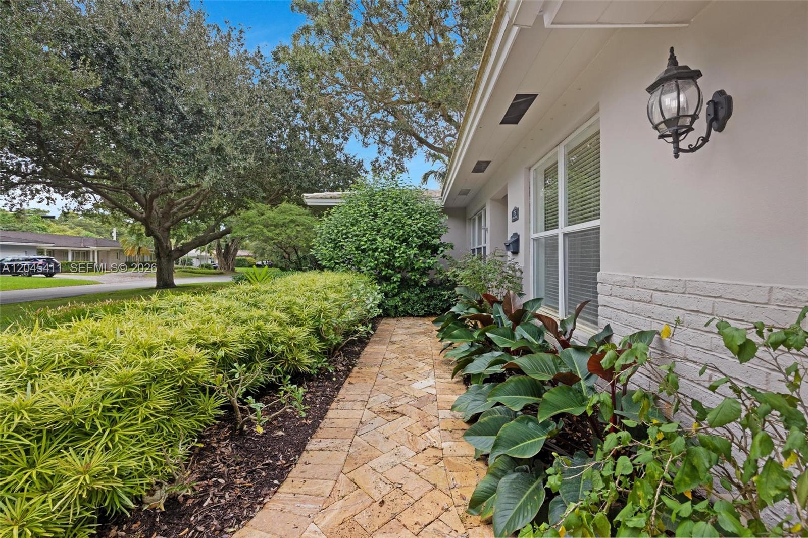 A stone walkway leads along the side of a house with landscaping and trees — 1246 Algardi Ave, Coral Gables FL 33146, CORAL GABLES, FL