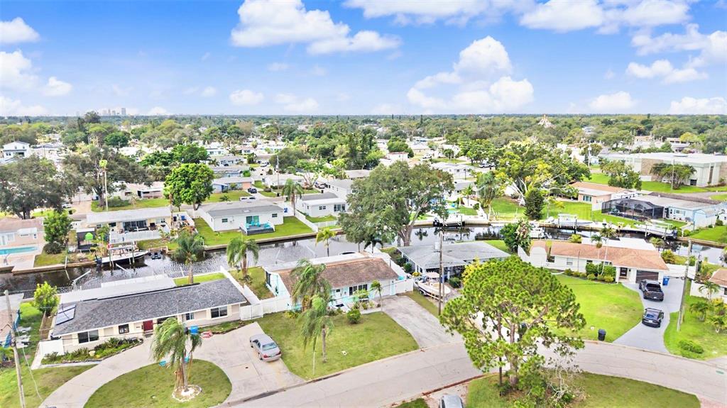An aerial view shows a residential neighborhood with houses situated along a narrow canal — 9472 TREASURE LANE NE, ST PETERSBURG, FL
